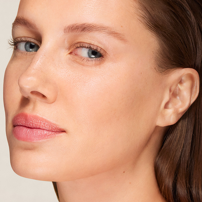 Frau mit reiner Haut trägt Augenpflege mit dem Finger auf