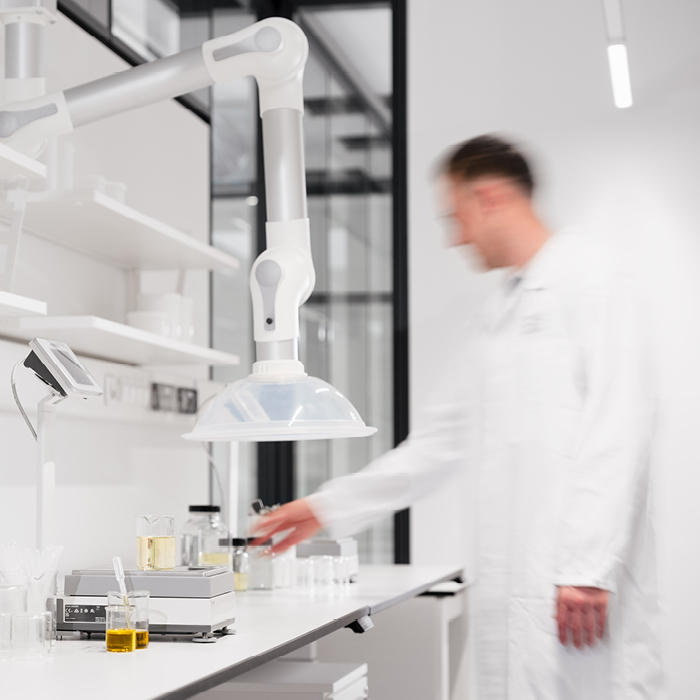 Ein Mann im Laborkittel arbeitet an einem Labortisch mit Geräten und einem Absaugsystem