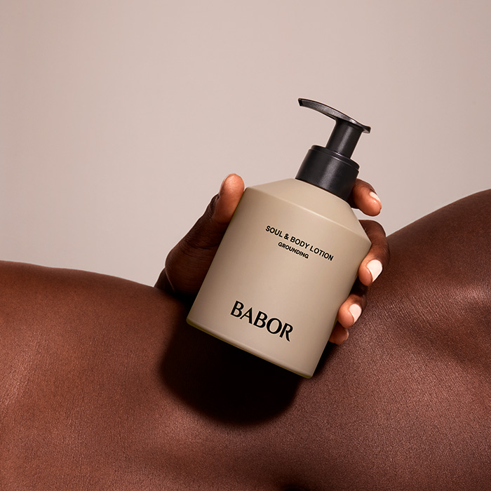 Close Up von schöner ebenmäßiger Haut und BABOR Bodylotion in der Hand